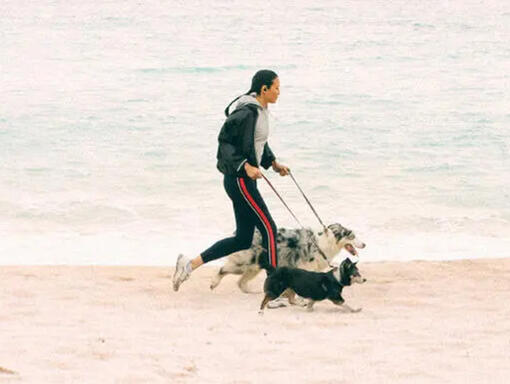 Una donna corre lungo la spiaggia con due cani